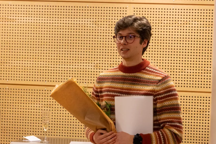 A person holding a flower bouquet and a sheet of paper.