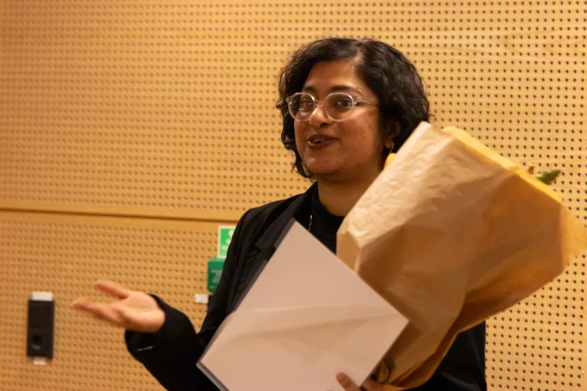 A person holding a flower bouquet and a sheet of paper.