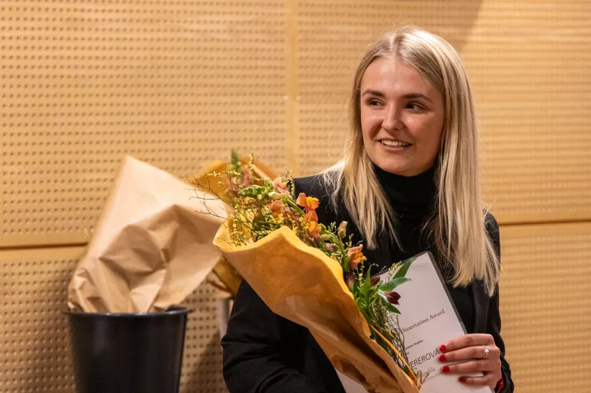 A person holding a flower bouquet and a sheet of paper.