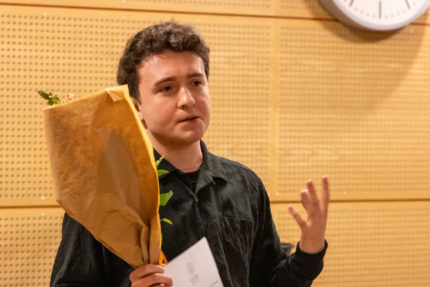 A person holding a flower bouquet and a sheet of paper.