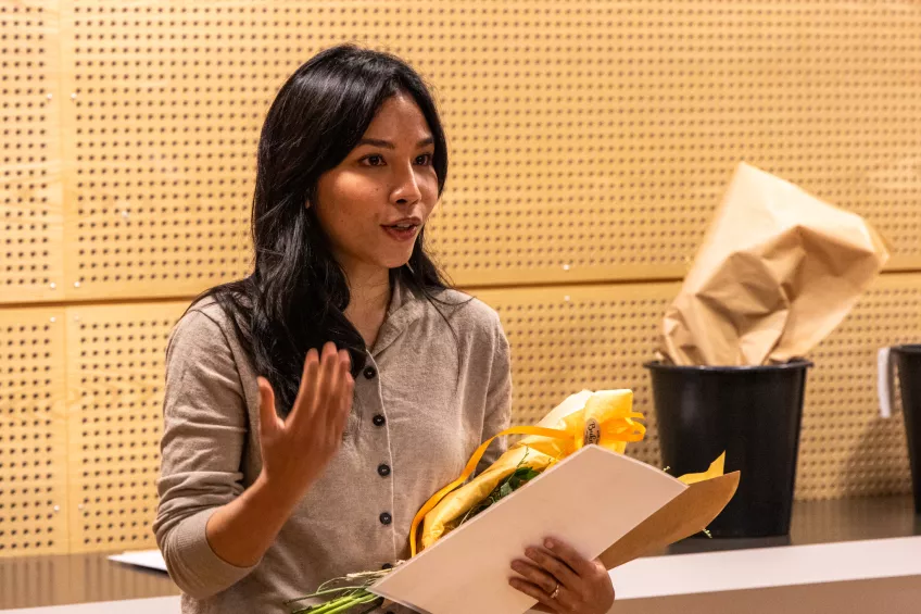 A person holding a flower bouquet and a sheet of paper.