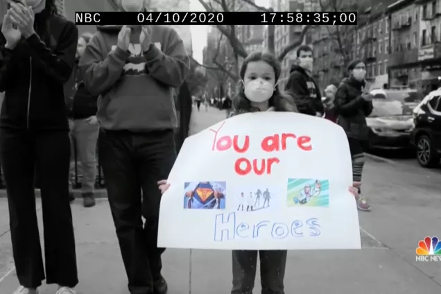 Ett barn som håller i ett plakat där det står "You are our heroes".